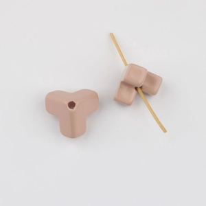 Close-up of pink acrylic Y-shaped triangle beads with a metal needle for DIY jewelry