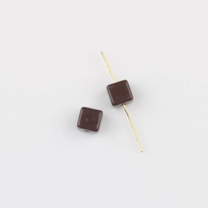 Macro detail of dark brown acrylic cube beads with hole showing the threading process
