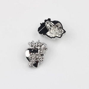 Gros plan de boutons en alliage de cœur avec motifs floraux et attaches métalliques au dos