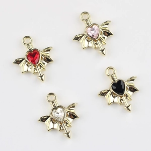 Macro view of gold alloy wing and heart pendants with colorful zircon inlay for DIY jewelry