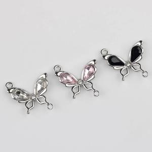Detalle macro de colgantes de mariposa con pedrería y perlas para joyería DIY