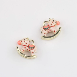 Close-up of pink enamel rocking horse pendants with gold alloy finish for DIY jewelry