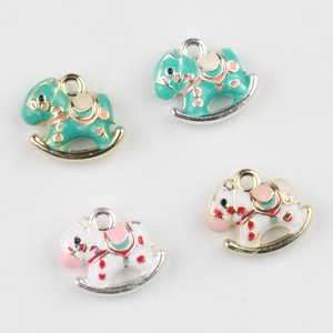 Close-up of mint green and cream enamel rocking horse pendants for DIY jewelry making