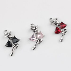 Dettaglio macro di tre ciondoli a rosa con gemme a cuore nei colori nero, rosa e rosso