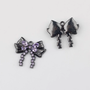 Detalle de dije de moño en metal negro con circonitas púrpuras para joyas DIY