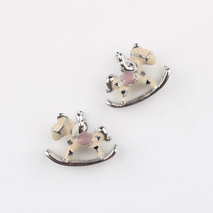Close-up of enamel rocking horse charms for DIY jewelry making in pink and white