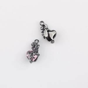 Makroaufnahme von Gunmetal-Herzanhänger mit rosa Zirkon und geschnitzten Rosendetails