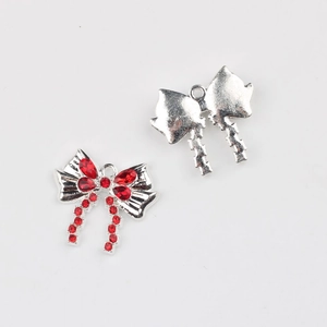 Detalle del colgante de lazo plateado con circonitas rojas para joyería DIY