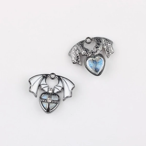 Detail of gothic wing heart pendants with white enamel and blue glitter star patterns