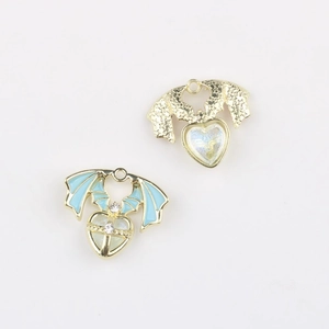 Close-up of DIY heart wing pendants with blue enamel, gold plating and zircon inlay