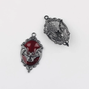 Detalle macro del colgante de murciélago gótico con esmalte rojo y patrones florales de plata