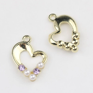 Detailed view of heart-shaped gold alloy pendants with pearls and purple zircons for DIY