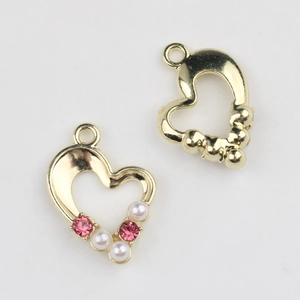 Macro view of gold heart pendants with pink rhinestones and white pearls for DIY jewelry