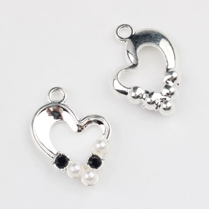 Close-up of heart-shaped alloy charms with pearl and zircon inlay for DIY jewelry