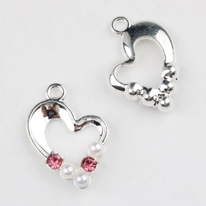Detailed view of silver heart charms with pink rhinestones and white pearls for DIY jewelry