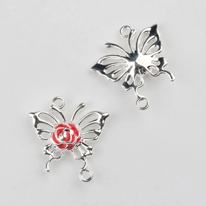 Detalle de colgantes de mariposa plateada con rosa de esmalte rojo y bucles dobles
