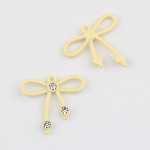 Detalle de colgantes de lazo amarillo crema con pedrería para creación de joyas DIY