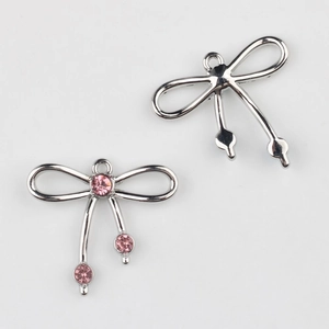 Detalle de colgantes de lazo plateado con strass rosa para joyería artesanal