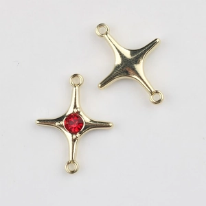 Macro shot of gold star charms with red zircon inlay and double connector loops for DIY jewelry