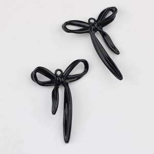 Primer plano de dos colgantes de lazo en esmalte negro brillante para joyería artesanal