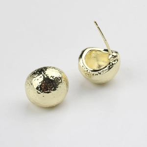 Détail de boucles d'oreilles dorées avec texture martelée et design sphérique arrondi