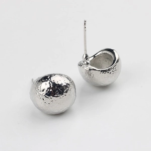 Détail macro de boucles d'oreilles sphériques argentées avec texture martelée et tige S925