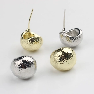 Détails de la texture martelée des boucles d'oreilles sphériques dorées et argentées