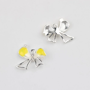 Macro detail of yellow enamel bow pendant with pearls and silver alloy textured back