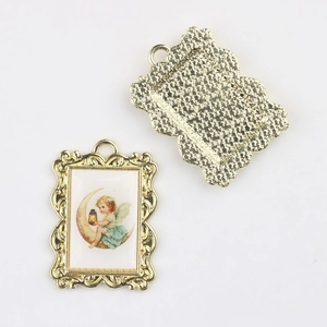 Detail of vintage gold alloy angel pendant showing embossed scrolls and textured back