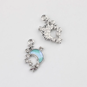 Close-up of crescent moon pendant charms with blue gradient enamel and small rhinestones