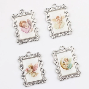 Close-up of four silver vintage alloy angel pendants with baroque embossed frames for DIY