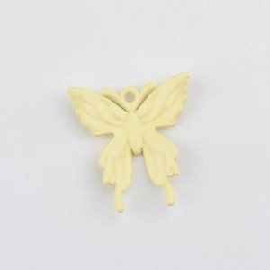 Makro-Detail eines creme-gelben Emaille-Schmetterlingsanhängers mit glatter Metalloberfläche