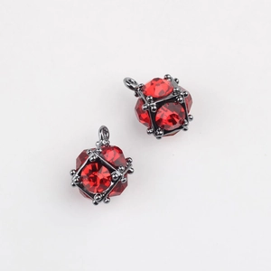 Macro detail of cube-shaped jewelry pendants with red crystals and dark metal cages