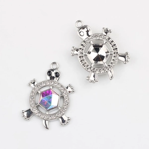 Détail macro de pendentifs tortue avec gemmes irisées et accents de zircon brillant