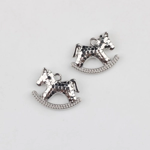 Close-up of silver rocking horse pendant with textured honeycomb surface and rhinestones