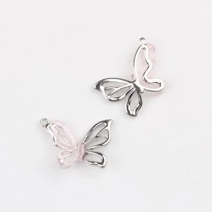 Détail de pendentifs papillon en résine rose avec cadres métalliques argentés
