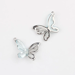Vue détaillée de deux breloques papillon en résine bleu clair avec monture en argent