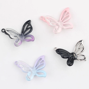 Gros plan de quatre pendentifs papillons en résine colorée avec anneaux pour bijoux DIY