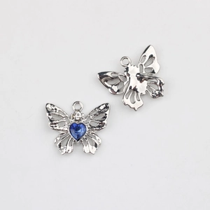 Détail macro du pendentif papillon avec pierre bleue en cœur et ailes en métal argenté
