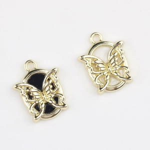 Detailed close-up of golden butterfly charms with black resin inlay for DIY jewelry making
