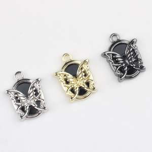 Macro view of butterfly alloy charms with resin inlay in gold, silver, and black finishes