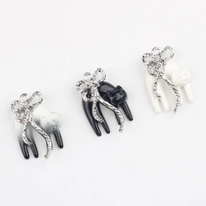 Detailweergave van DIY kattenhangers met zilveren strikjes in zwart en wit email