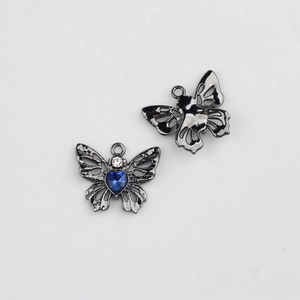 Détail d'un pendentif papillon noir avec gemme cœur bleue pour création de bijoux DIY