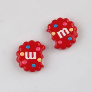 Macro shot of red acrylic cookie-shaped DIY charms with colorful dots and letter m