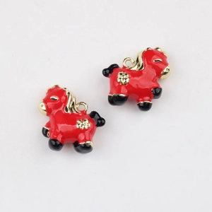 Macro detail of red enamel horse charms with golden floral patterns for DIY jewelry