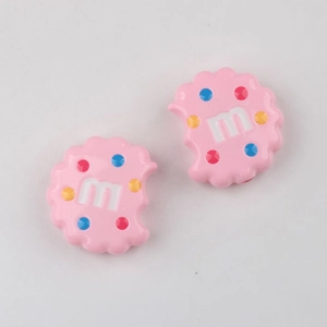 Close-up of pink bitten-cookie acrylic charms with colorful dots and letter m pattern
