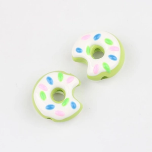 Nahaufnahme von angebissenen Donut-Acrylperlen mit grüner Glasur und bunten Streuseln für DIY