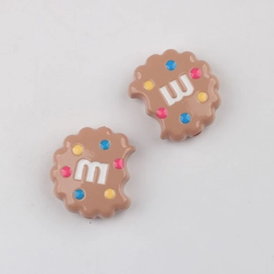 Detail of DIY cookie beads with colorful dots and letter M on brown resin base