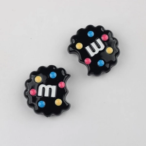 Detail of black acrylic cookie beads with m-letter and colorful dots for DIY crafts