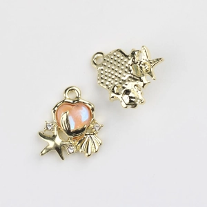 Macro view of gold ocean charms with pink heart gems and seashell metal textures